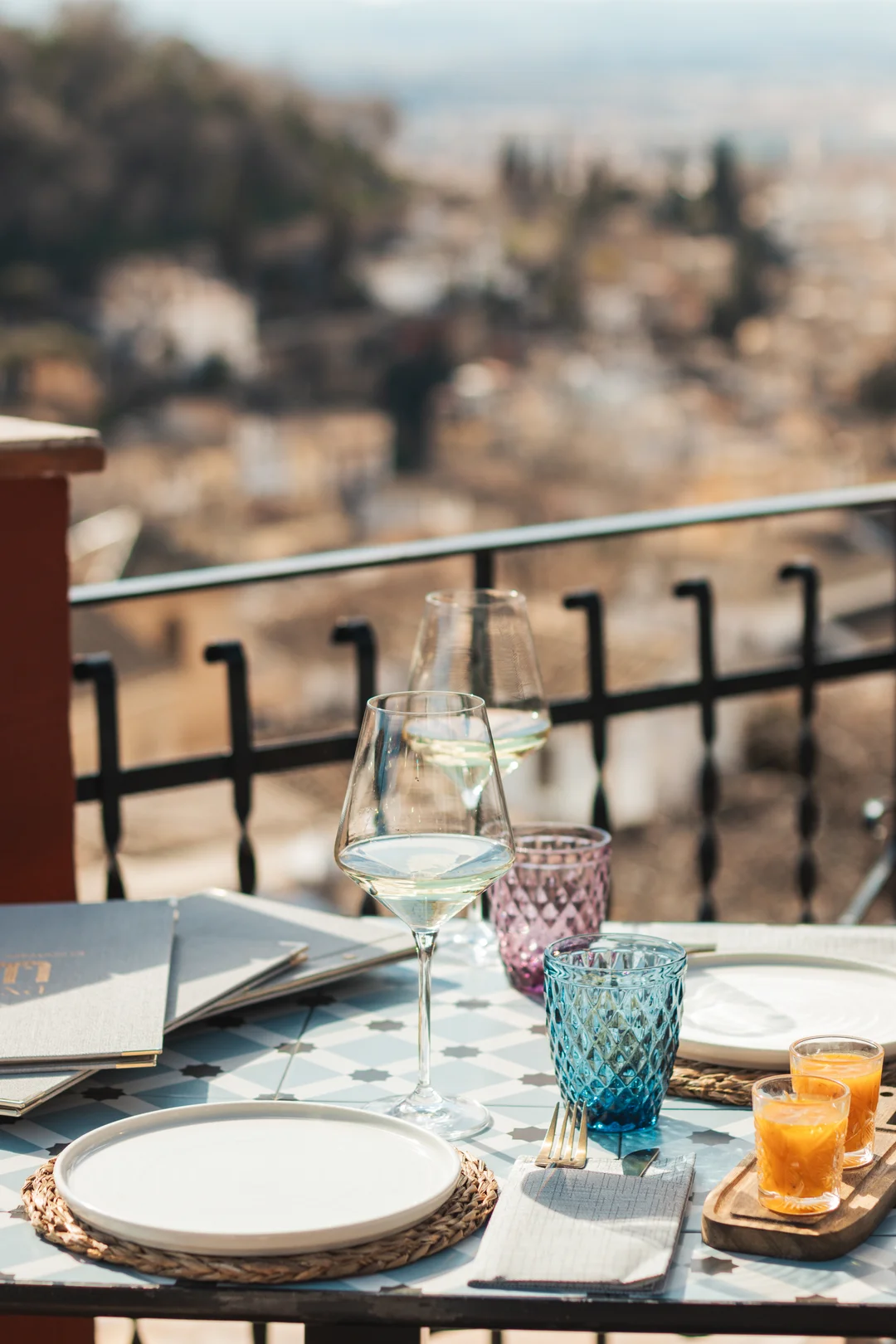 A romantic table setting for two with chilled wine glasses on a sun-drenched terrace in the Albaicín district of Granada, capturing the golden hour atmosphere perfect for proposals and couples in Andalusia. A romantic table setting for two with chilled wine glasses on a sun-drenched terrace in the Albaicín district of Granada, capturing the golden hour atmosphere perfect for proposals and couples in Andalusia.