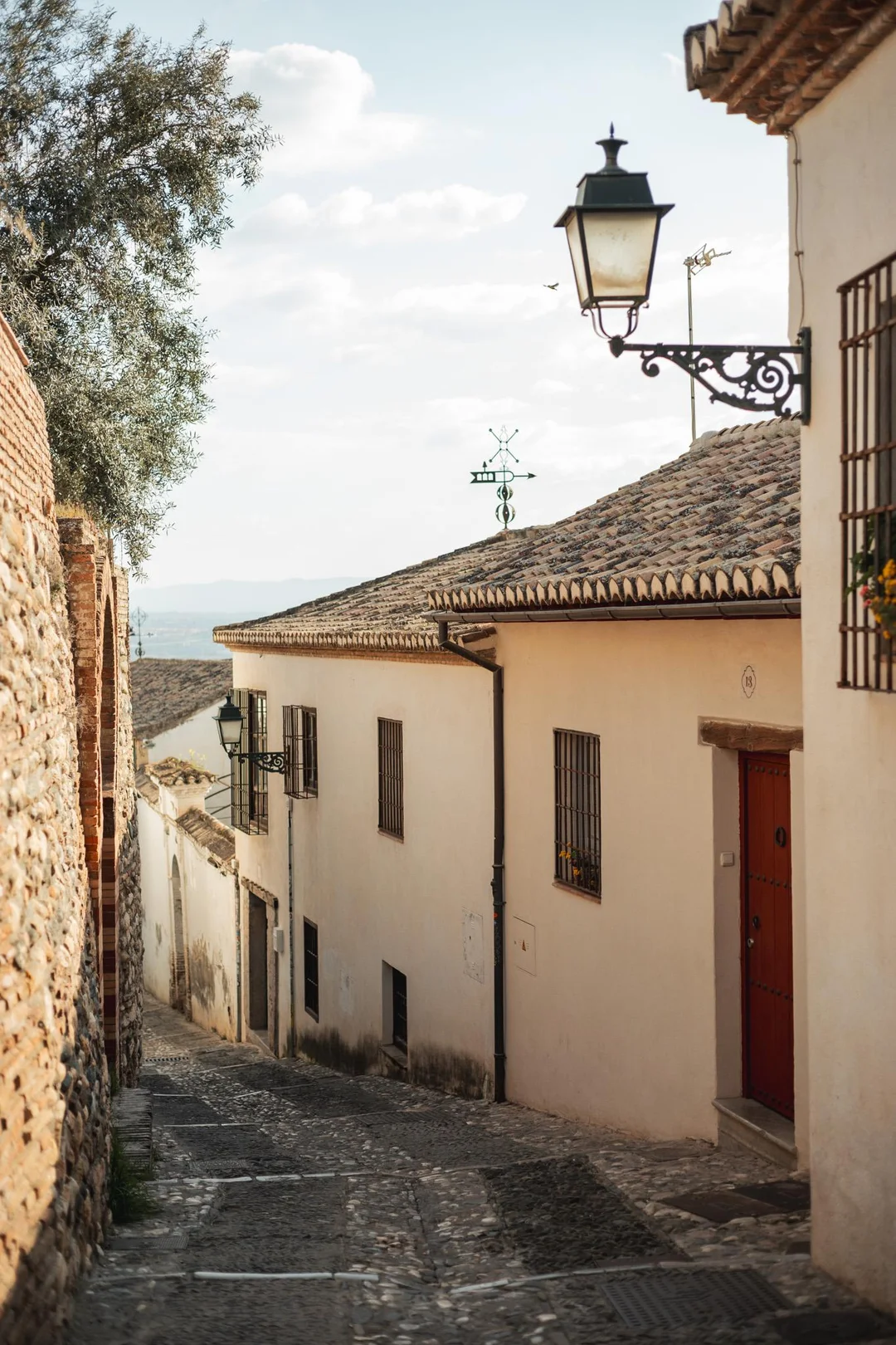 A narrow cobblestone street with whitewashed houses and vintage lanterns in the historic Albaicín district of Granada, showcasing timeless historical Andalusian architecture captured by Zihman Photo. A narrow cobblestone street with whitewashed houses and vintage lanterns in the historic Albaicín district of Granada, showcasing timeless historical Andalusian architecture captured by Zihman Photo.