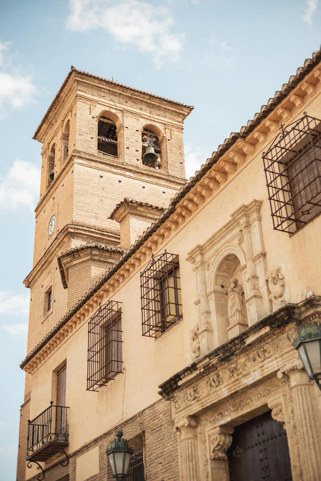 Low-angle view of the historic Iglesia de Santa Ana featuring intricate historical Andalusian architecture and a classic bell tower in the heart of Granada's Albaicín district. Low-angle view of the historic Iglesia de Santa Ana featuring intricate historical Andalusian architecture and a classic bell tower in the heart of Granada's Albaicín district.