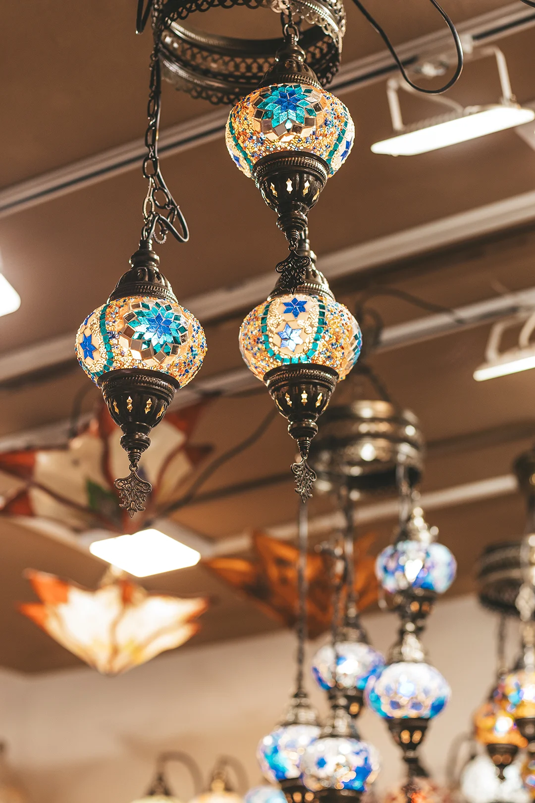 Intricate, glowing mosaic glass lamps hanging in a traditional shop, evoking the romantic atmosphere of historical Andalusian architecture found in the Albaicín district of Granada. Intricate, glowing mosaic glass lamps hanging in a traditional shop, evoking the romantic atmosphere of historical Andalusian architecture found in the Albaicín district of Granada.